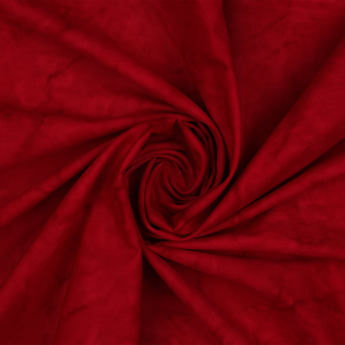 A close-up of deep red fabric arranged in a spiral swirl, showing the material texture and color.