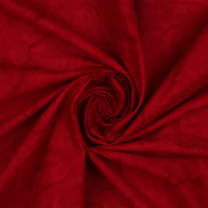 A close-up of deep red fabric arranged in a spiral swirl, showing the material texture and color.