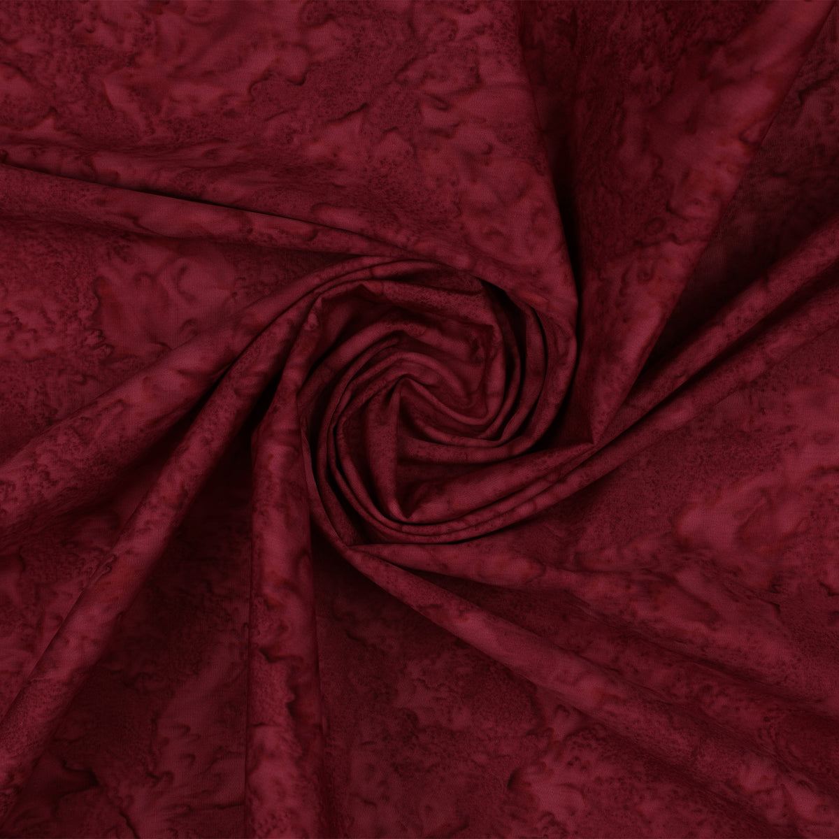 Deep burgundy fabric with a mottled pattern, arranged in a central spiral drape.