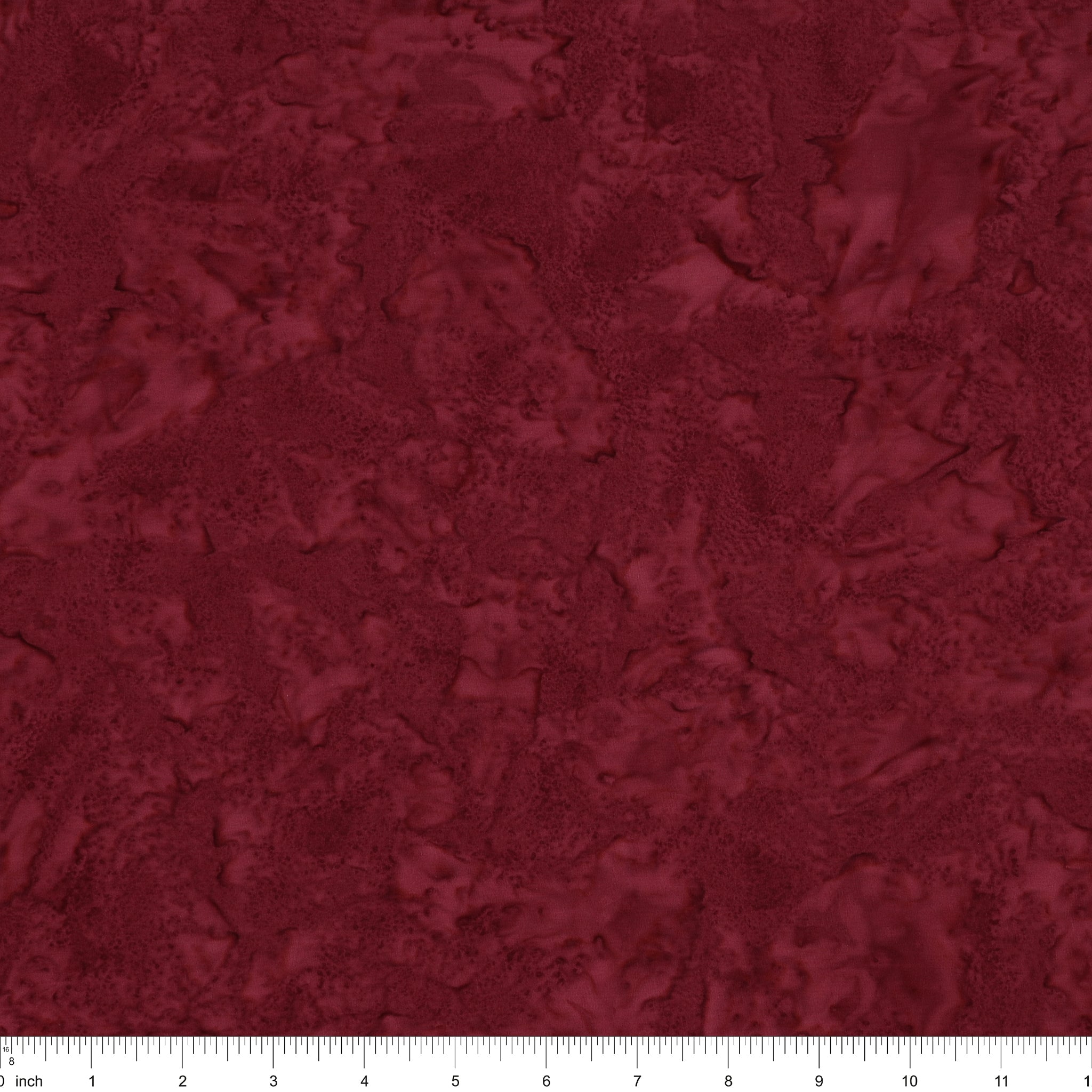A close-up of a dark red marbled or textured material swatch with a ruler scale visible along the bottom edge.