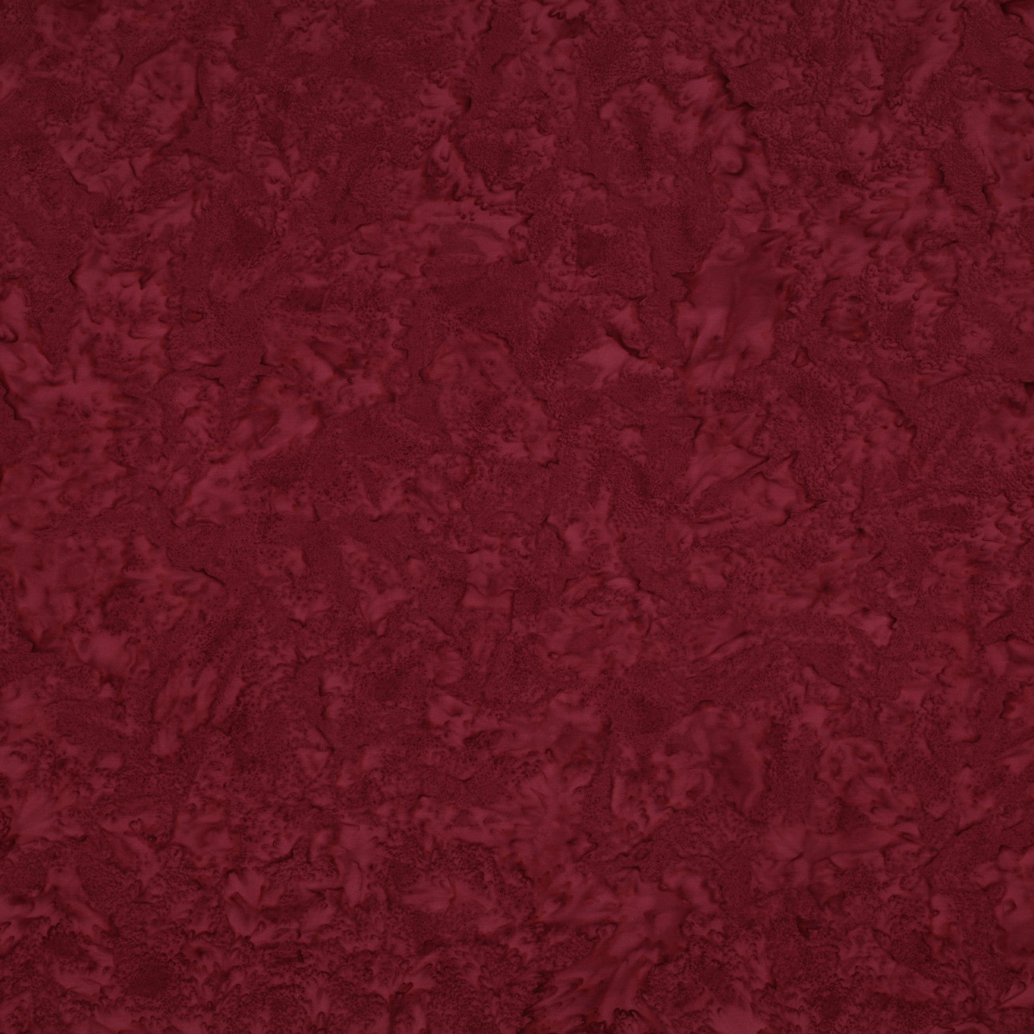 Sassy batik fabric with rich burgundy mottling and raspberry-red highlights.