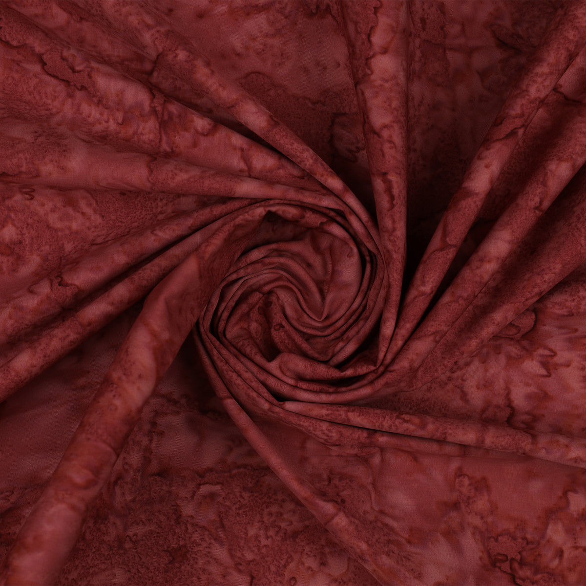 A close-up of draped maroon fabric with a mottled, tie-dye style pattern, arranged in a spiral swirl.