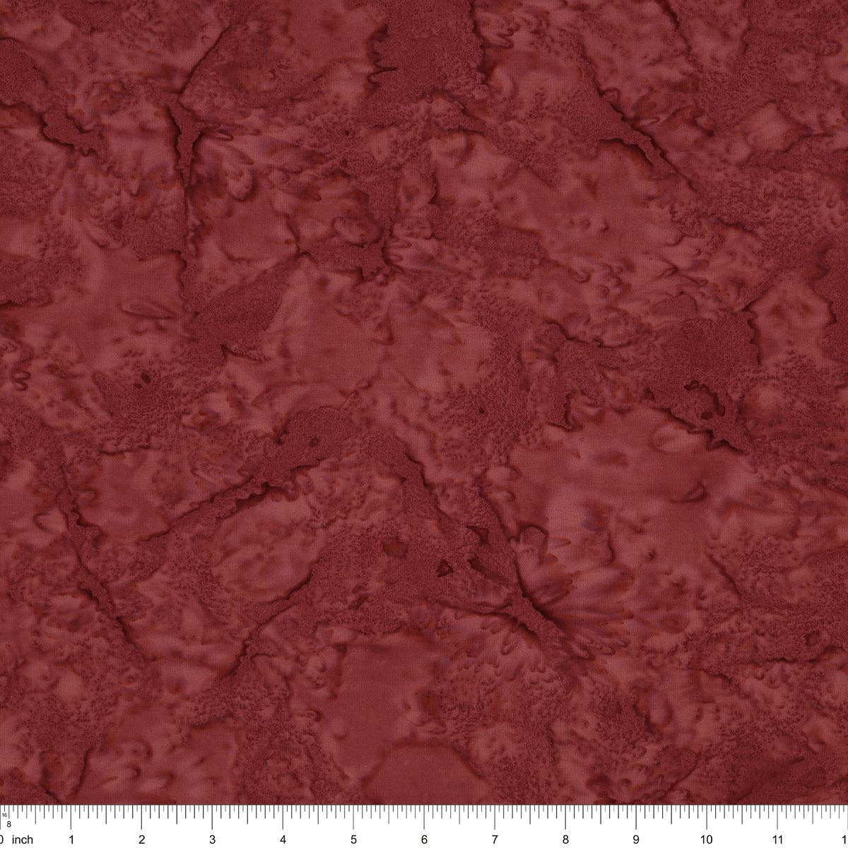 A close-up of a marbled fabric in a deep reddish-brown or burgundy shade, with a white ruler along the bottom edge showing scale.
