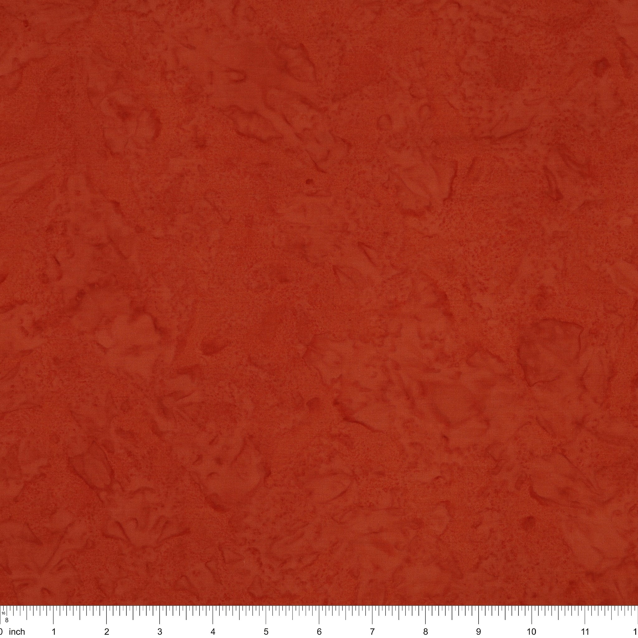 A close-up of a textured terracotta or rust-colored fabric, showing a mottled, slightly distressed surface. A white ruler with black markings is visible along the bottom edge to indicate scale.