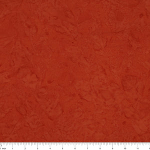 A close-up of a textured terracotta or rust-colored fabric, showing a mottled, slightly distressed surface. A white ruler with black markings is visible along the bottom edge to indicate scale.