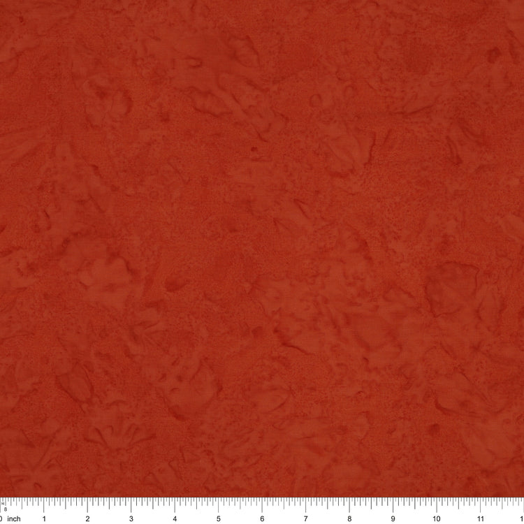 A close-up of a textured terracotta or rust-colored fabric, showing a mottled, slightly distressed surface. A white ruler with black markings is visible along the bottom edge to indicate scale.