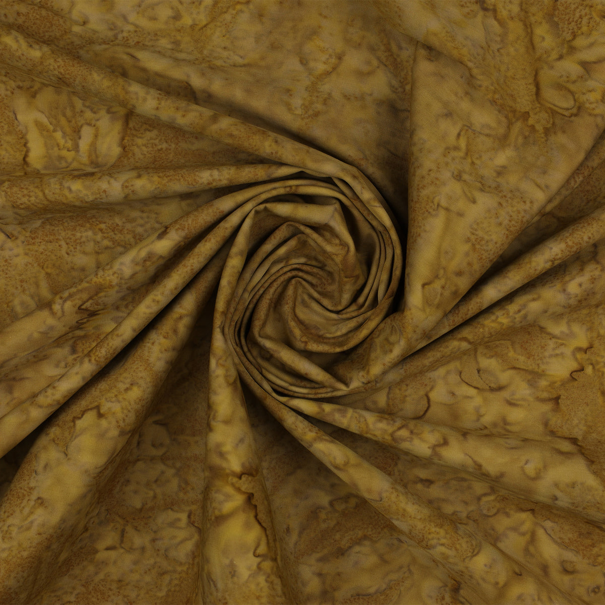 A close-up of draped fabric with a mottled, marbled pattern in warm golden brown, tan, and olive tones, arranged in a spiral fold.
