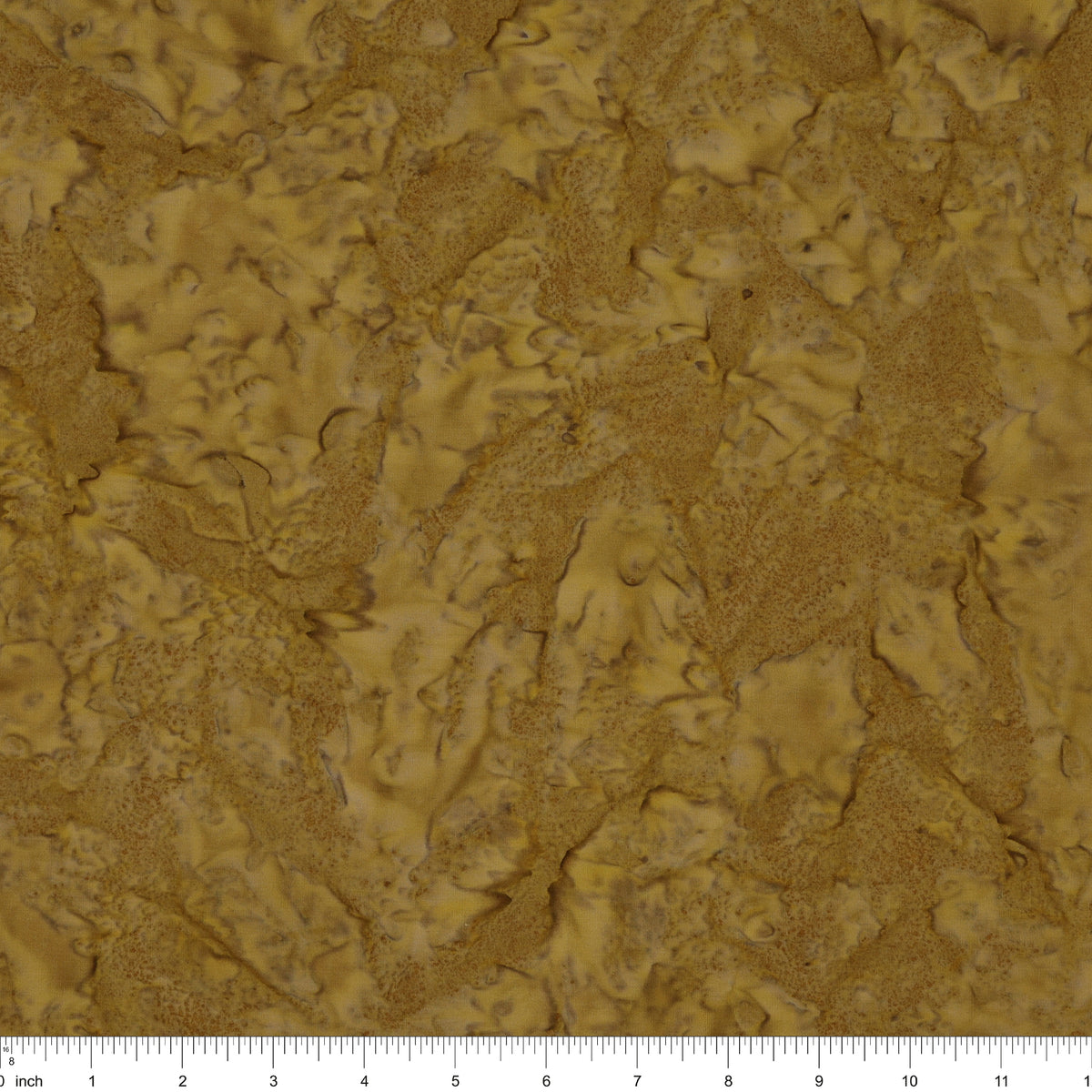 A close-up of a textured material swatch in warm tan and brown tones, with a ruler scale visible along the bottom edge.