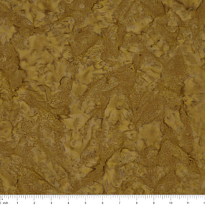 A close-up of a textured material swatch in warm tan and brown tones, with a ruler scale visible along the bottom edge.