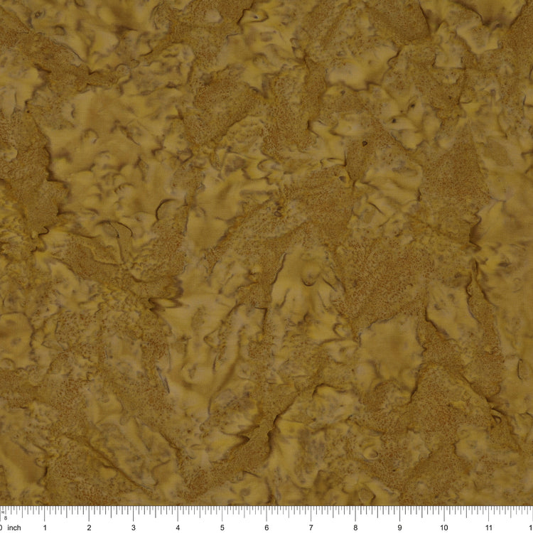 A close-up of a textured material swatch in warm tan and brown tones, with a ruler scale visible along the bottom edge.