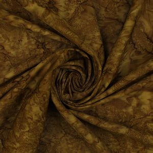 Brown and tan batik fabric draped in a spiral swirl pattern, showing a mottled organic print.