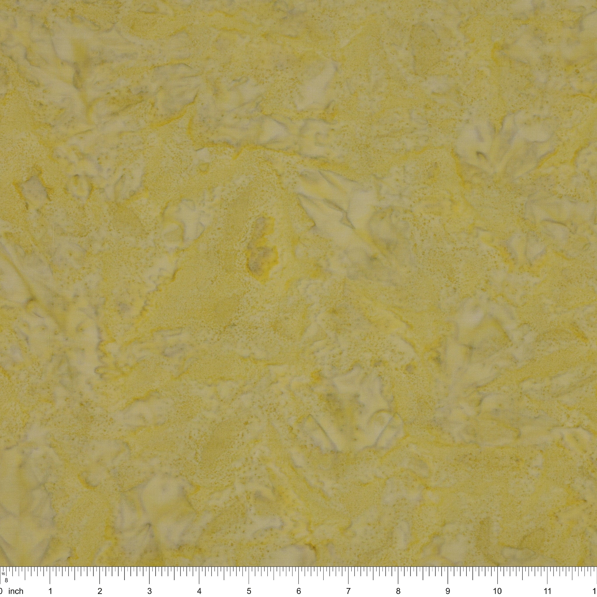 A close-up of a textured fabric in pale yellow with irregular white marbled patterns, with a ruler scale visible along the bottom edge.