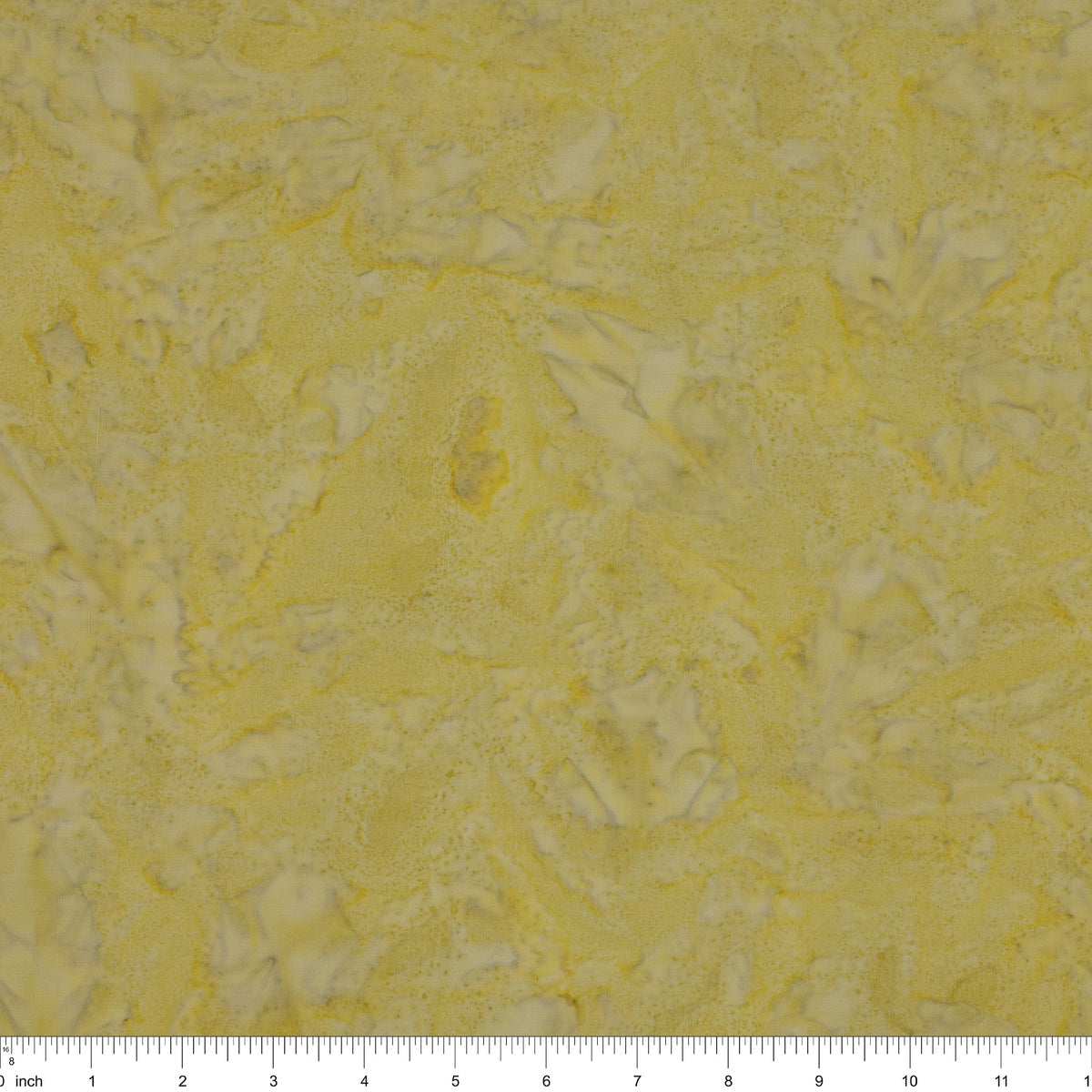 A close-up of a textured fabric in pale yellow with irregular white marbled patterns, with a ruler scale visible along the bottom edge.