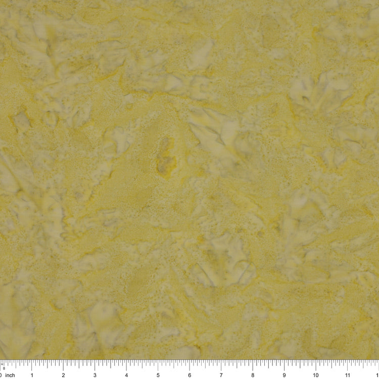 A close-up of a textured fabric in pale yellow with irregular white marbled patterns, with a ruler scale visible along the bottom edge.
