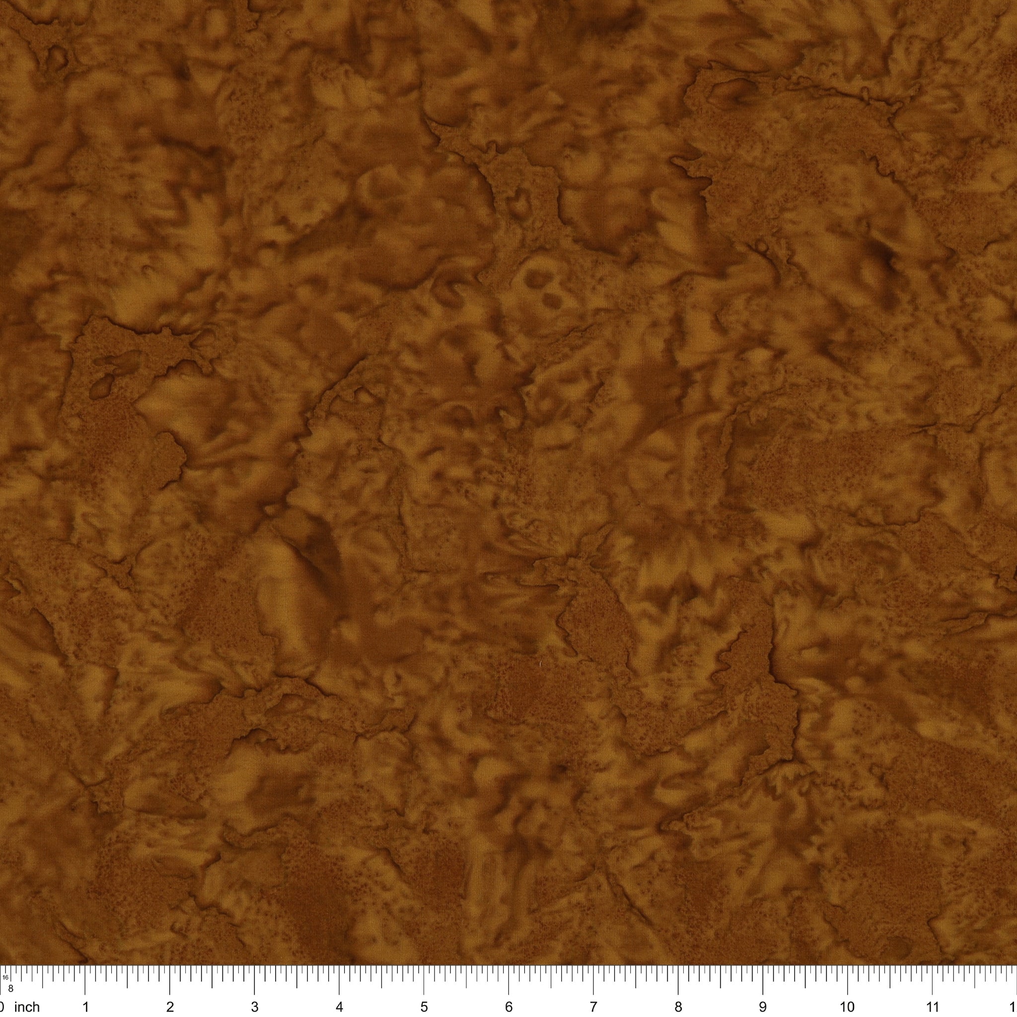 A close-up of a brown textured material with an organic, cracked or leaf-like surface pattern, shown with a ruler along the bottom edge for scale.