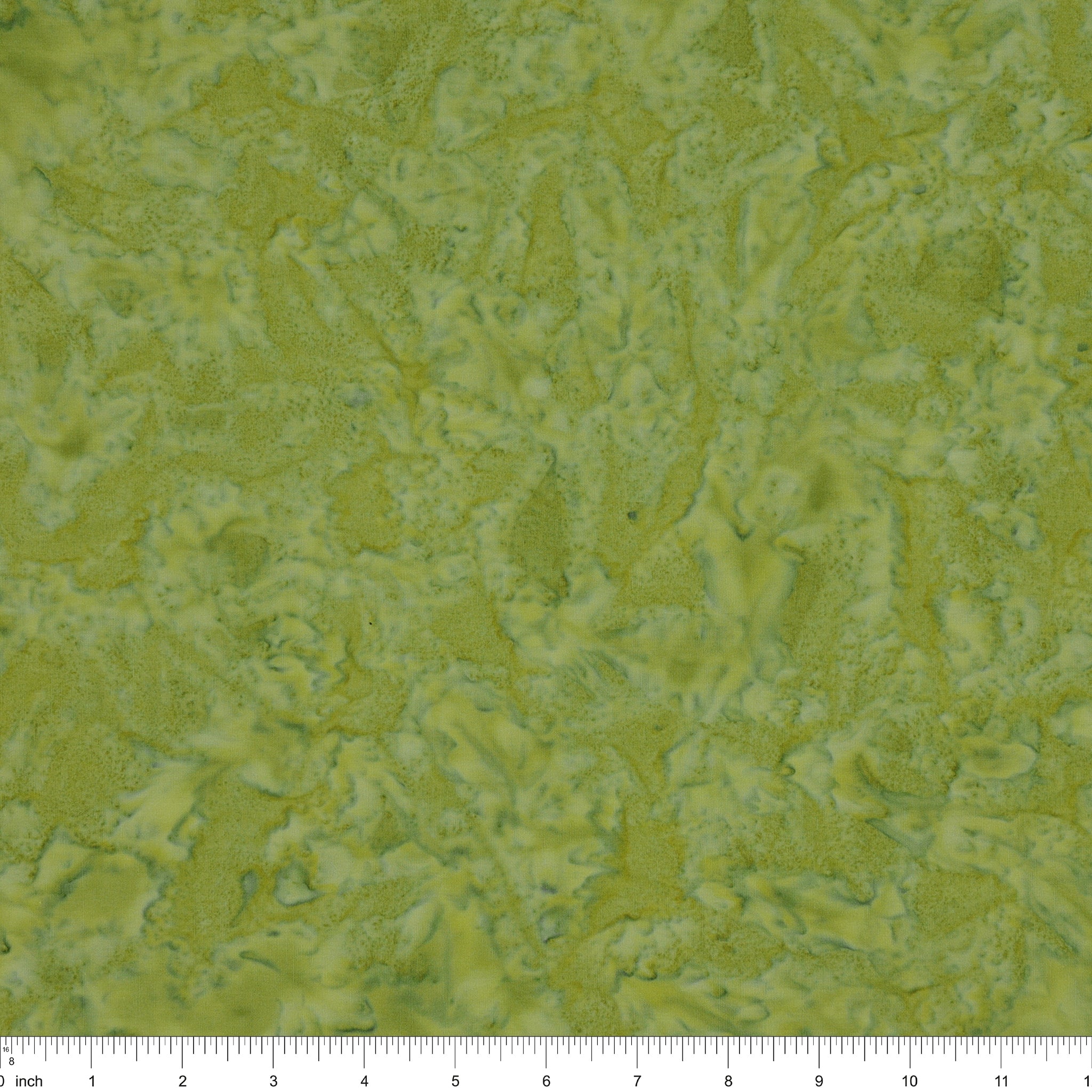 A close-up of a textured fabric in mottled olive green and yellow-green tones, with a ruler along the bottom edge showing scale.