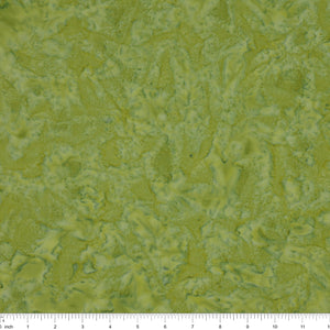 A close-up of a textured fabric in mottled olive green and yellow-green tones, with a ruler along the bottom edge showing scale.
