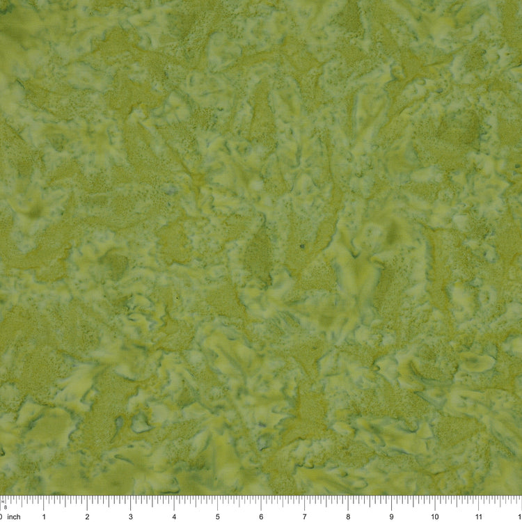 A close-up of a textured fabric in mottled olive green and yellow-green tones, with a ruler along the bottom edge showing scale.