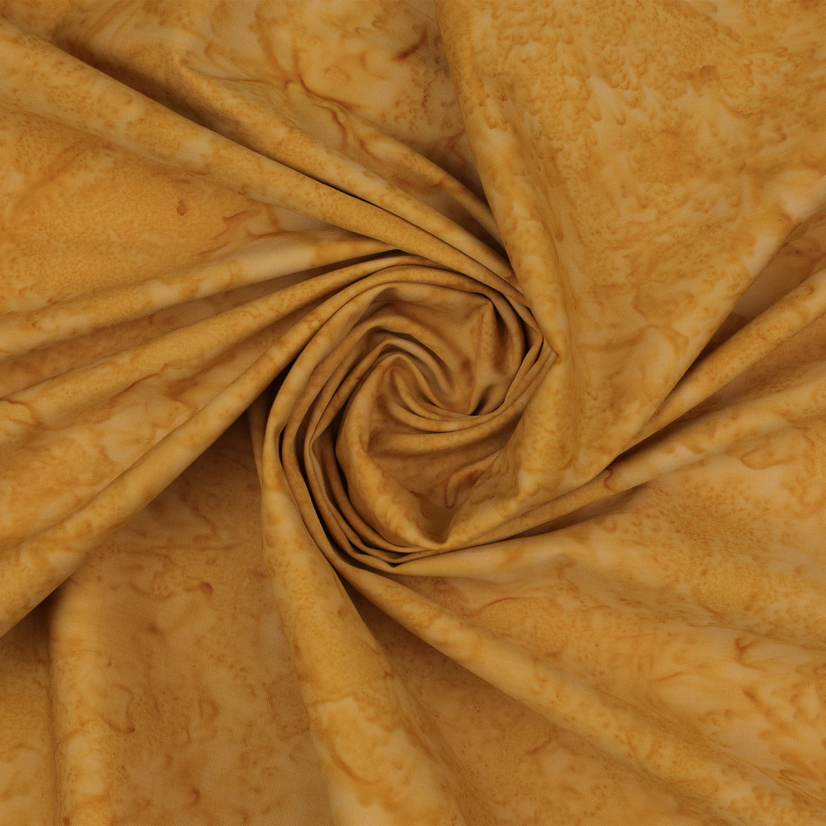 A close-up of draped fabric with a marbled pattern in warm golden yellow and tan tones, arranged in a spiral fold.