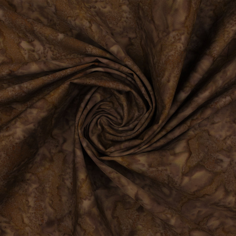 Brown batik fabric with a mottled organic pattern, draped in a spiral swirl to show its texture and drape.