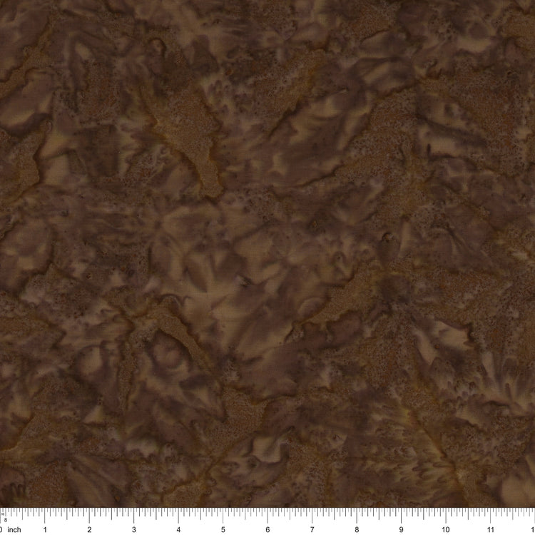 Brown batik fabric with a mottled, marbled pattern in shades of dark and light brown, featuring a 12-inch fabric ruler along the bottom edge.