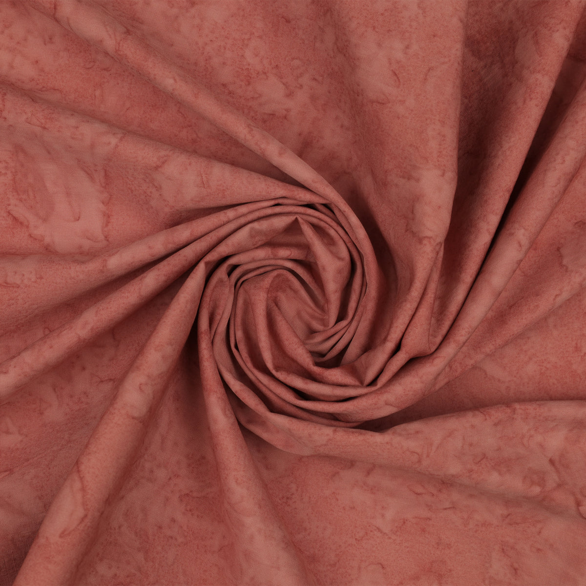 A close-up of draped dusty rose fabric with a subtle mottled or marbled texture, arranged in a spiral fold pattern.