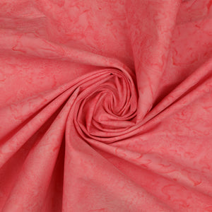 A close-up of coral pink fabric with a subtle marbled or mottled pattern, arranged in a spiral drape to show texture and color variation.