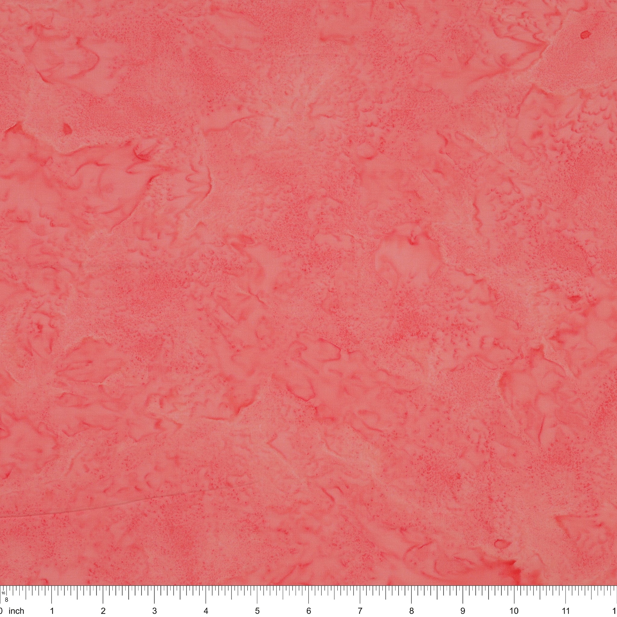 A close-up of a textured coral pink fabric with a subtle mottled or marbled pattern, featuring a white ruler scale at the bottom edge.