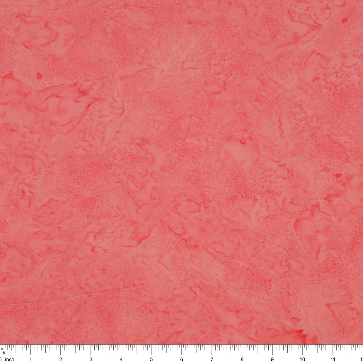 A close-up of a textured coral pink fabric with a subtle mottled or marbled pattern, featuring a white ruler scale at the bottom edge.