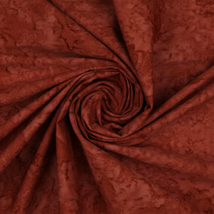 A close-up of draped fabric in a swirling spiral, showing a mottled reddish-brown pattern with darker shading.