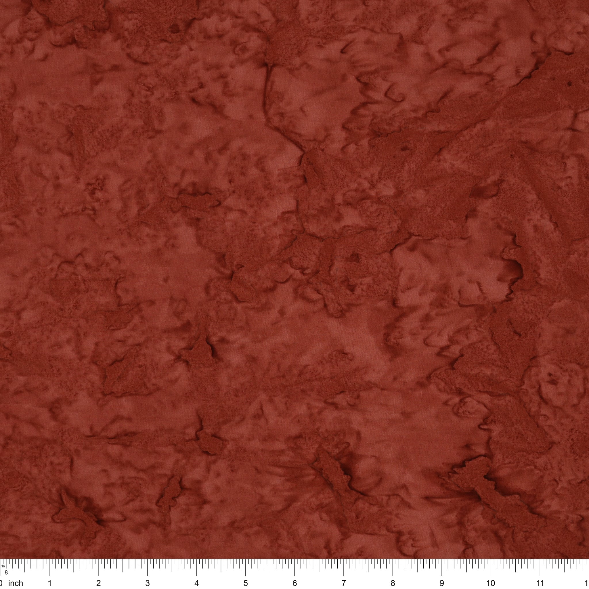 A close-up of a textured fabric or material swatch in a warm rust red color, with a ruler scale visible along the bottom edge.