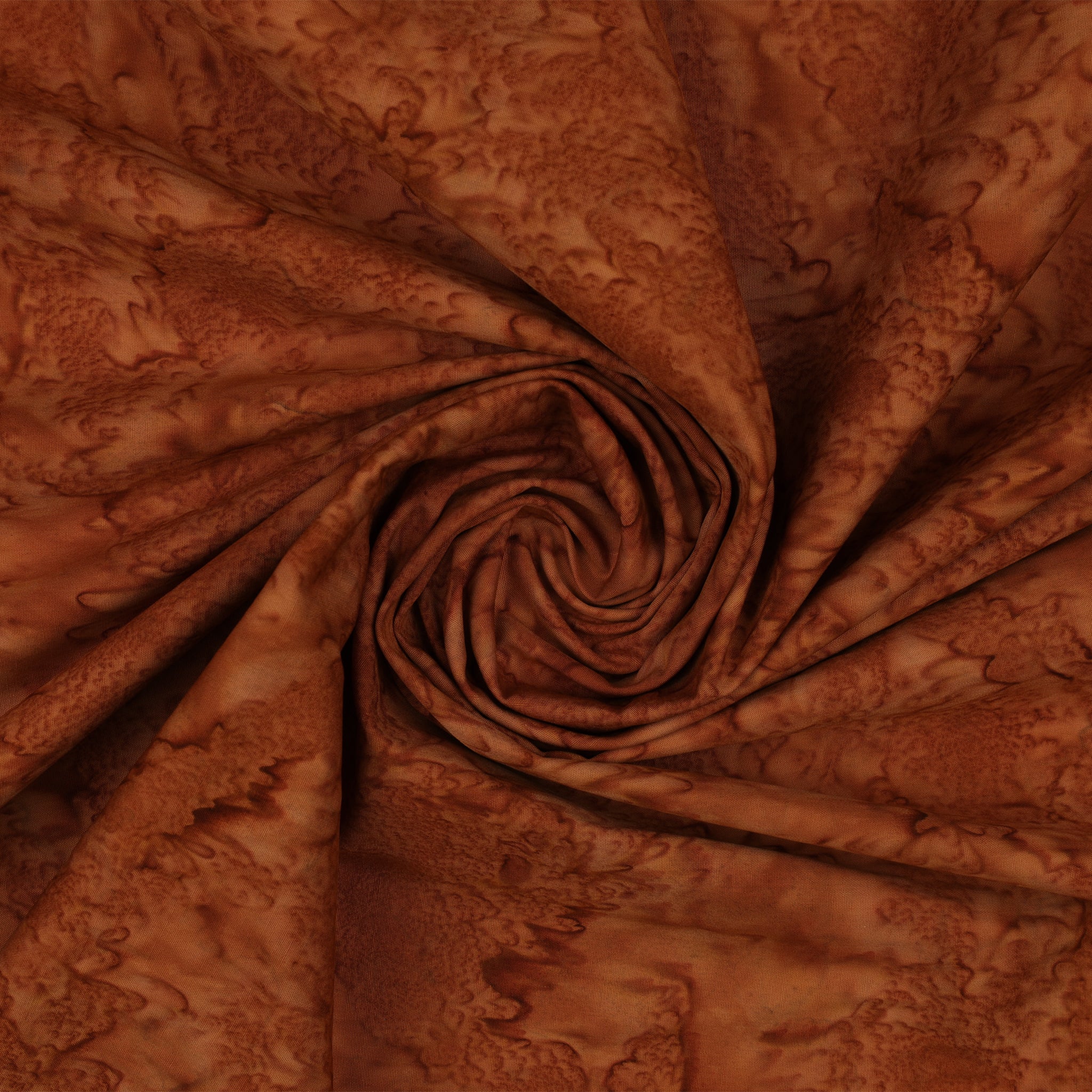 Brown batik fabric with a mottled abstract pattern, arranged in a spiral drape to show texture and color variation.