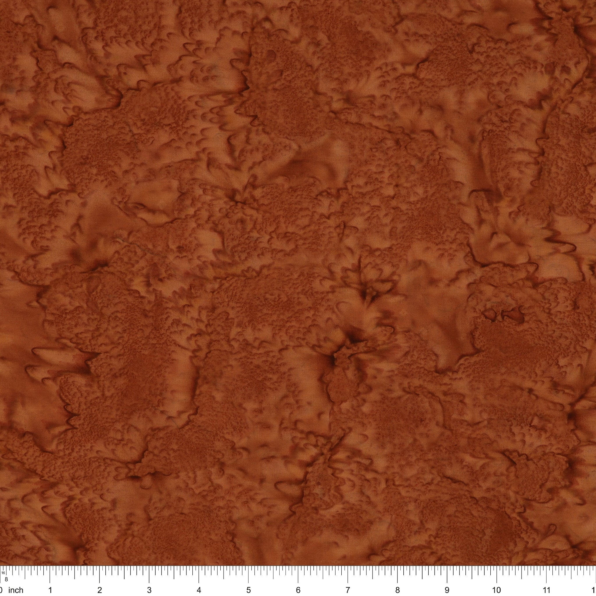 A close-up of a textured brown material swatch with an organic, marbled surface pattern, featuring a white ruler scale at the bottom edge.