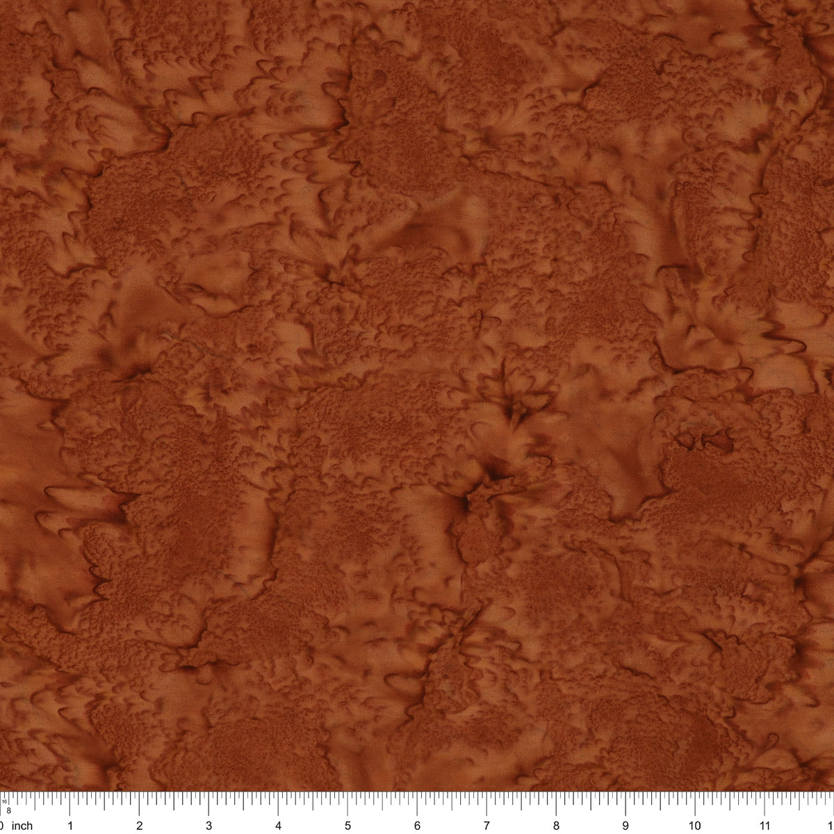 A close-up of a textured brown material swatch with an organic, marbled surface pattern, featuring a white ruler scale at the bottom edge.