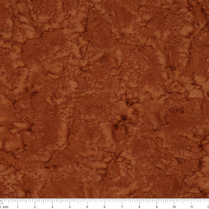A close-up of a textured brown material swatch with an organic, marbled surface pattern, featuring a white ruler scale at the bottom edge.