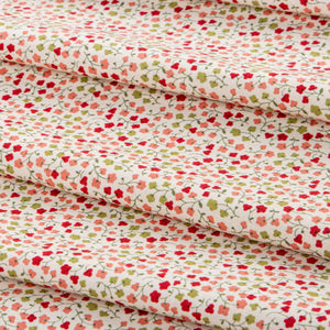 A close-up of folded fabric with a dense small floral print on a warm off-white background. The pattern features red, pink, and light green flowers with thin green stems and leaves.