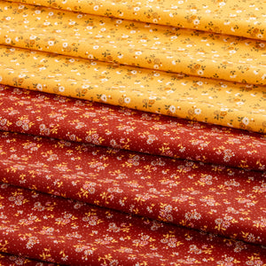 Stacked fabric pieces with a small floral print, showing two main colors: a bright yellow top layer and a rust red bottom layer, both decorated with tiny white flowers and green stems.