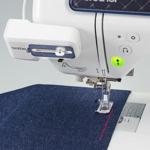 A close-up of a Brother sewing machine stitching a dark blue textured fabric, with the Brother logo visible on the machine arm and a laser guide.