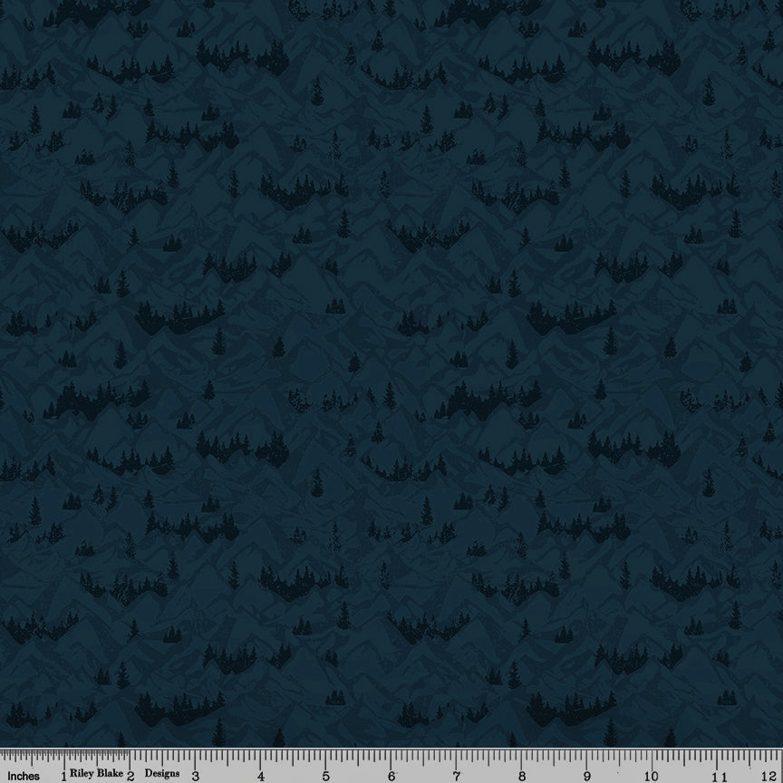 Navy blue fabric with layered mountain ranges and dark evergreen forest silhouettes with ruler for scale.