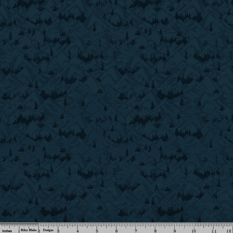 Navy blue fabric with layered mountain ranges and dark evergreen forest silhouettes with ruler for scale.