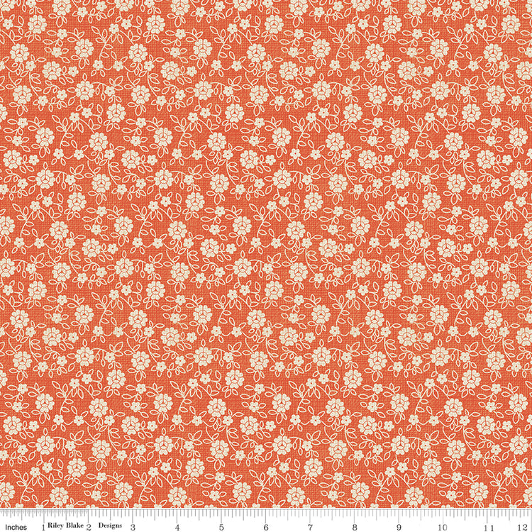Floral pattern fabric swatch on an orange background with a ruler along the bottom for scale. 