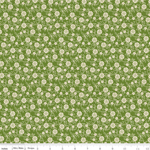 Floral pattern fabric with small white flowers on a green background with a ruler along the bottom for scale. 