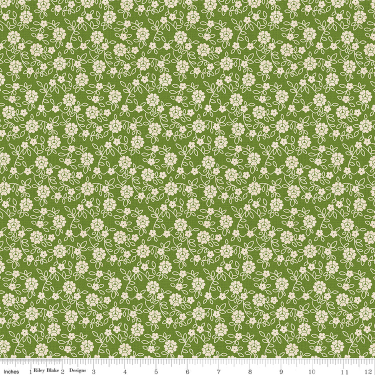 Floral pattern fabric with small white flowers on a green background with a ruler along the bottom for scale. 