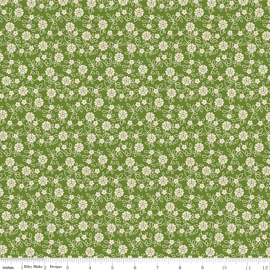 Floral pattern fabric with small white flowers on a green background with a ruler along the bottom for scale. 