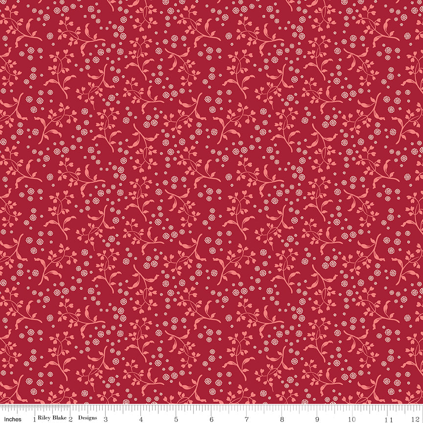 A repeating floral pattern featuring light pink vines and small white blossoms on a deep red background. Ruler along the bottom for scale. 