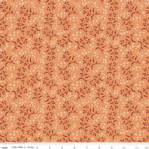 A seamless repeating pattern featuring delicate dark reddish-brown floral vines and small cream-colored dots on a warm peach-orange background. Ruler along the bottom for scale. 