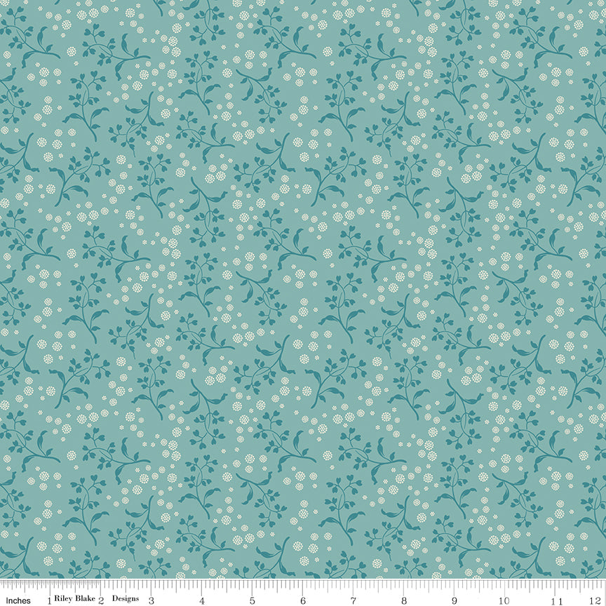 Floral patterned fabric with small white flowers on a teal background with a ruler along the bottom for scale. 