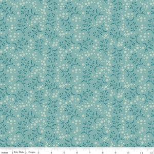 Floral patterned fabric with small white flowers on a teal background with a ruler along the bottom for scale. 