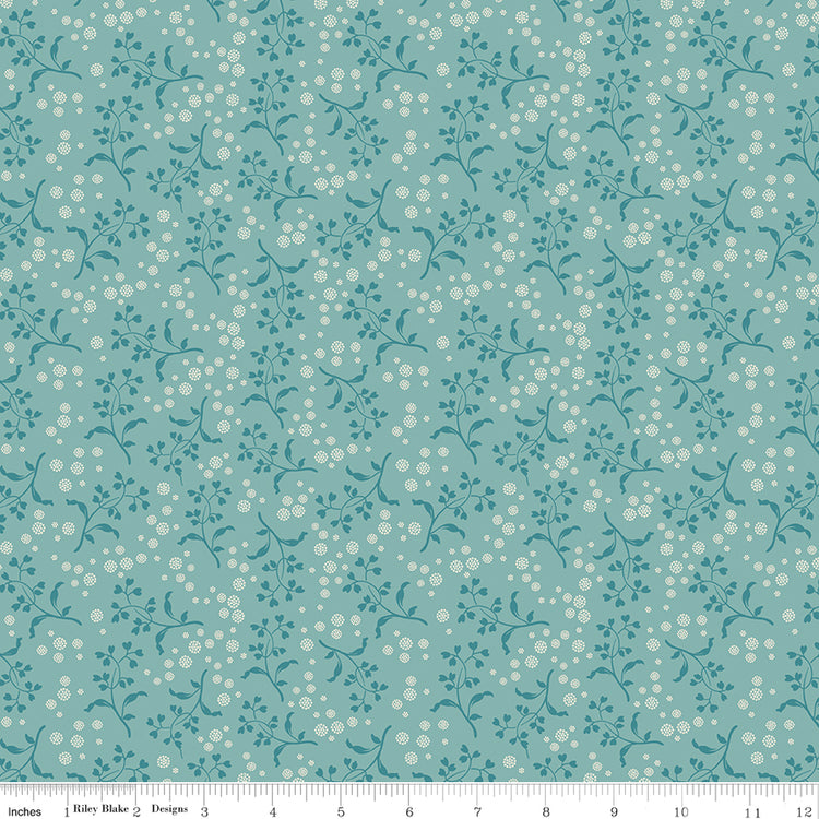 Floral patterned fabric with small white flowers on a teal background with a ruler along the bottom for scale. 