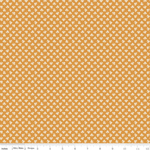 A repeating pattern of small white and muted gold plus signs on a dusty pink background, with a ruler along the bottom edge showing scale. 
